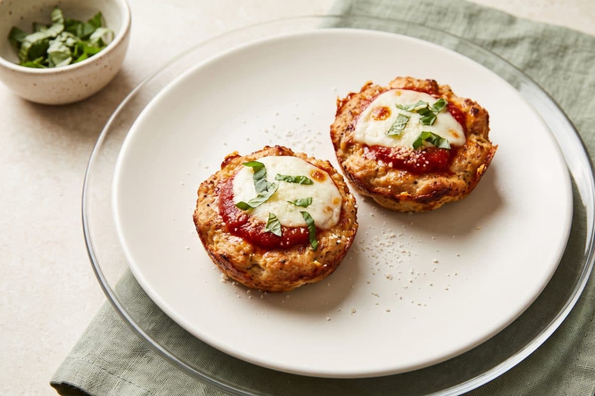 Baked Chicken Parmesan Cups, finished with grated Parmesan and basil, served as one portion on a white plate