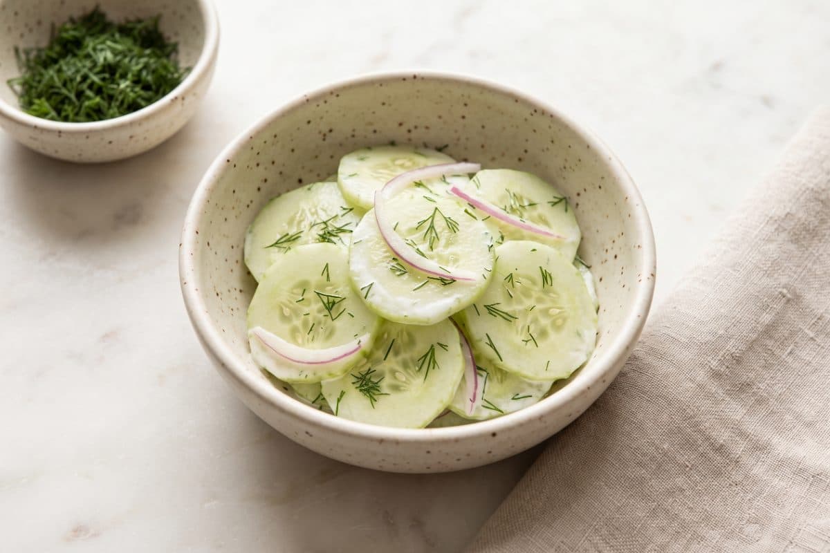 Cucumber Dill Salad, finished with dill, served as one portion in a speckled cream bowl