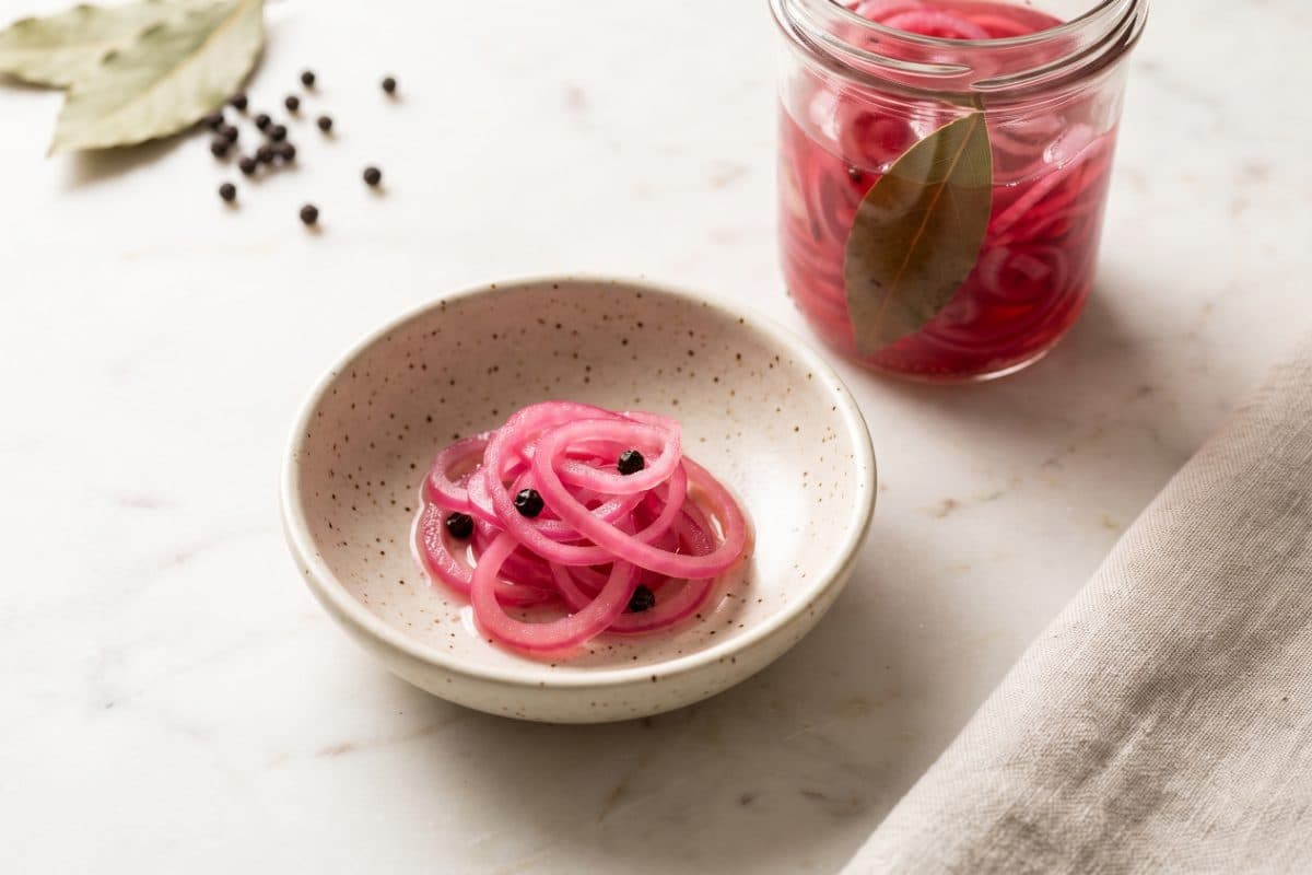 Quick Pickled Onions, served as one portion in a speckled cream bowl
