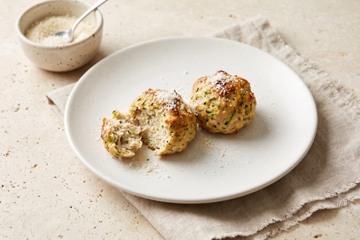 Turkey & Zucchini Meatballs, finished with grated Parmesan, served as one portion on a white plate