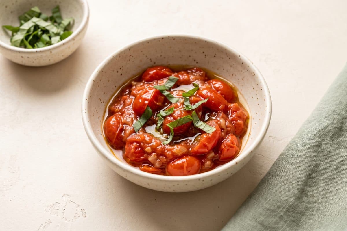 Warm Tomato Relish, finished with basil, served as one portion in a speckled cream bowl